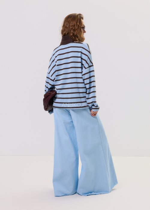 Niebieska bluzka damska w brązowe poziome paski z kołnierzykiem polo i luźnym krojem, prezentowana w stylizacji casual.