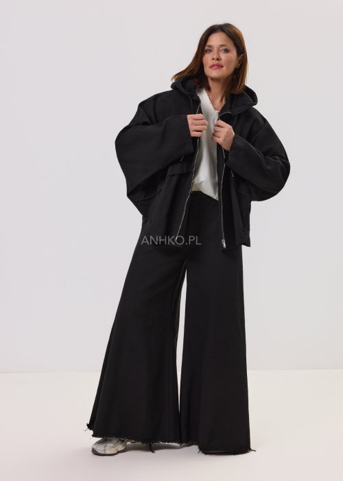 Czarna kurtka damska z kapturem zapinana na zamek, o luźnym kroju z szerokimi rękawami i kieszeniami, w stylu casual.