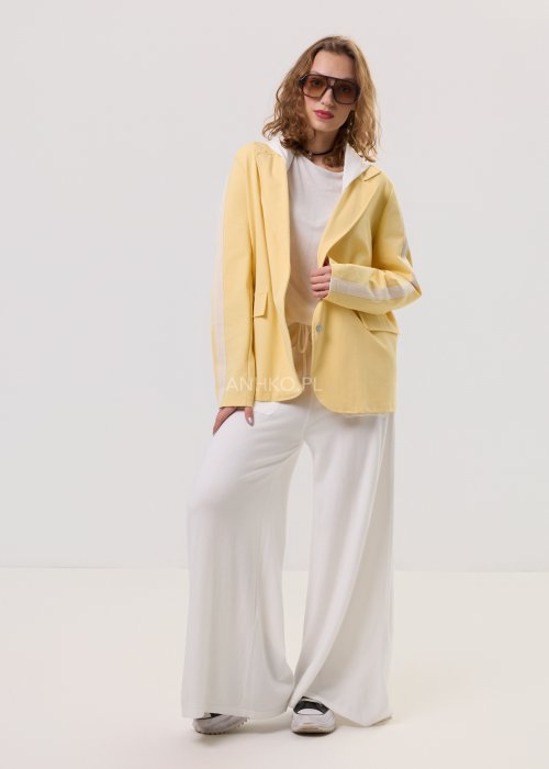 Żółta marynarka damska z kontrastowym kapturem i jasnymi lampasami na rękawach, zapinana na guziki, o luźnym kroju.
