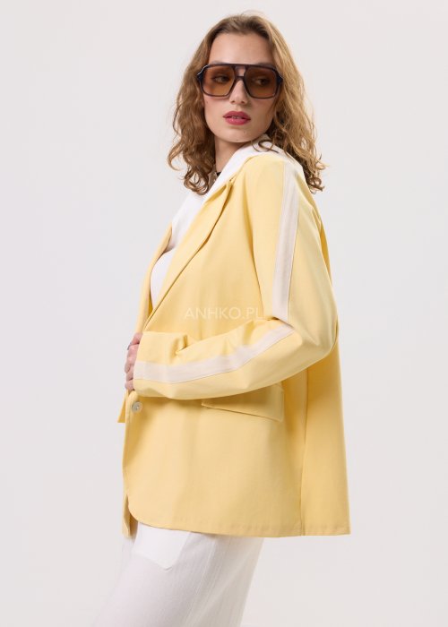 Żółta marynarka damska z kontrastowym kapturem i jasnymi lampasami na rękawach, zapinana na guziki, o luźnym kroju.