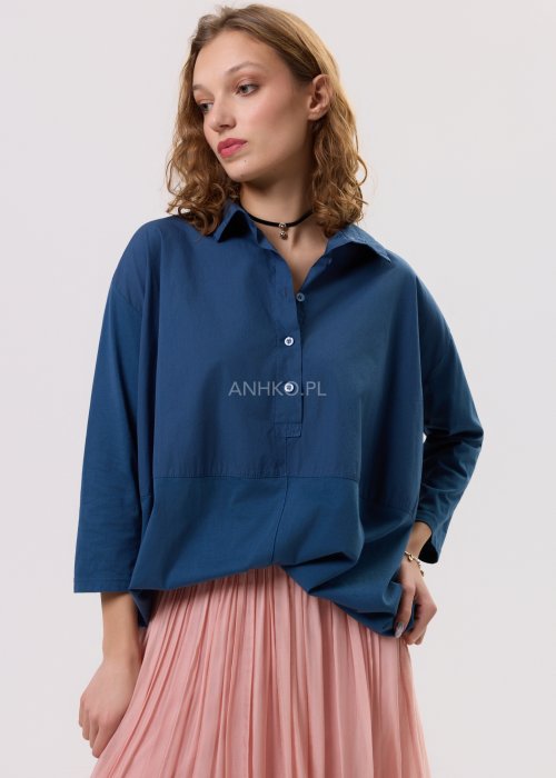 Granatowa koszula oversize z kołnierzykiem i zapięciem na guziki, o luźnym, swobodnym kroju z rękawem 3/4. Stylizacja z plisowaną spódnicą w delikatnym różowym kolorze w kobiecym, miejskim stylu.