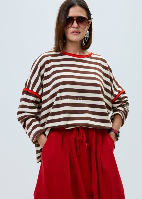 Bluzka damska w brązowo-beżowe paski o luźnym kroju. Model z długim rękawem oraz kontrastowym wykończeniem przy dekolcie i rękawach w kolorze czerwonym.