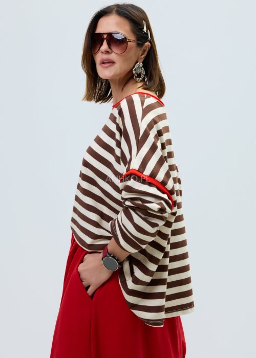 Bluzka damska w brązowo-beżowe paski o luźnym kroju. Model z długim rękawem oraz kontrastowym wykończeniem przy dekolcie i rękawach w kolorze czerwonym.