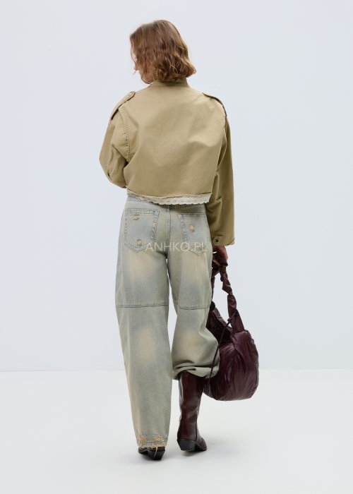 Krótka damska kurtka w kolorze camel z kieszeniami i ozdobnymi detalami, stylizowana z jasnymi jeansami.