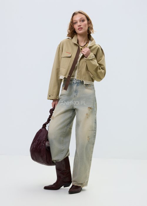Krótka damska kurtka w kolorze camel z kieszeniami i ozdobnymi detalami, stylizowana z jasnymi jeansami.