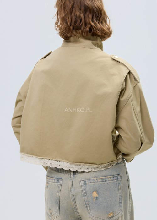 Krótka damska kurtka w kolorze camel z kieszeniami i ozdobnymi detalami, stylizowana z jasnymi jeansami.
