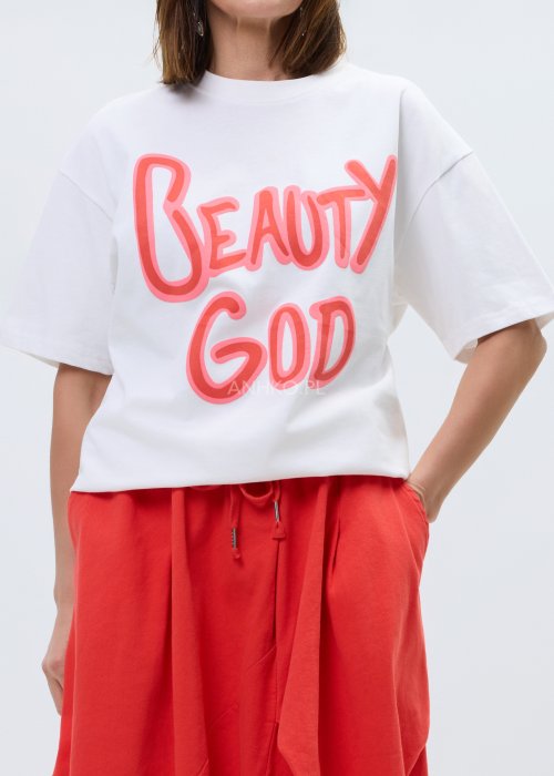 Biały T-shirt damski o luźnym kroju z krótkim rękawem i dużym nadrukiem „Beauty God” w neonowym różowym kolorze.