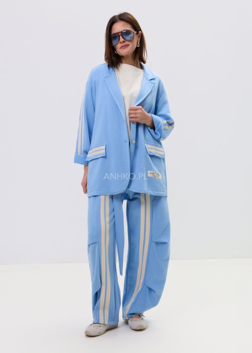 Niebieska damska marynarka oversize zapinana na guziki z kontrastowymi paskami na rękawach i kieszeniach.
