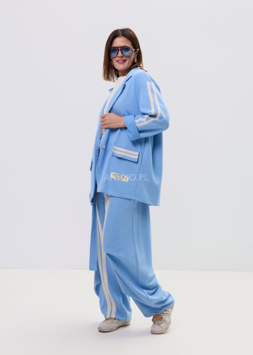 Niebieska damska marynarka oversize zapinana na guziki z kontrastowymi paskami na rękawach i kieszeniach.
