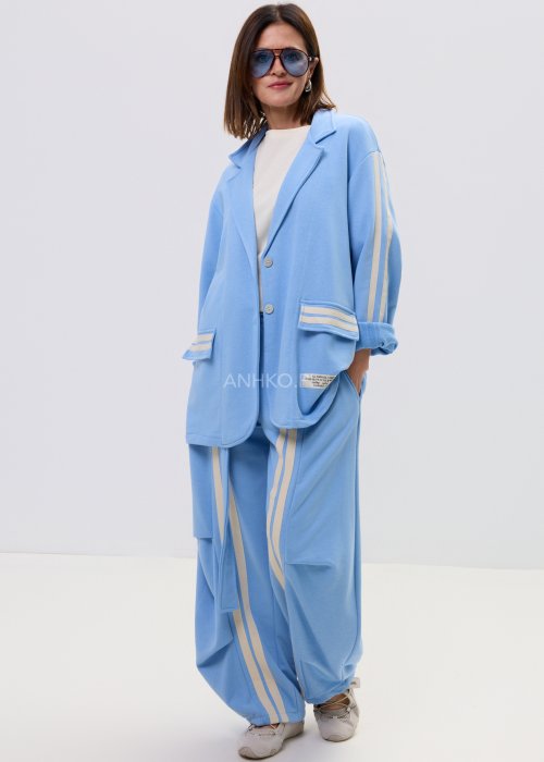 Niebieska damska marynarka oversize zapinana na guziki z kontrastowymi paskami na rękawach i kieszeniach.