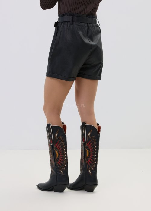 Czarne spodenki damskie z eco-skóry o luźnym kroju z wiązaniem w pasie, stylizacja miejska z marynarką i wysokimi botkami.