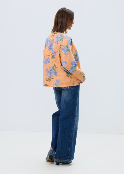 Damska bluza oversize w kolorze pomarańczowym z niebieskim kwiatowym wzorem, model z długim rękawem, zaokrąglonym dekoltem i kieszonką na piersi.
