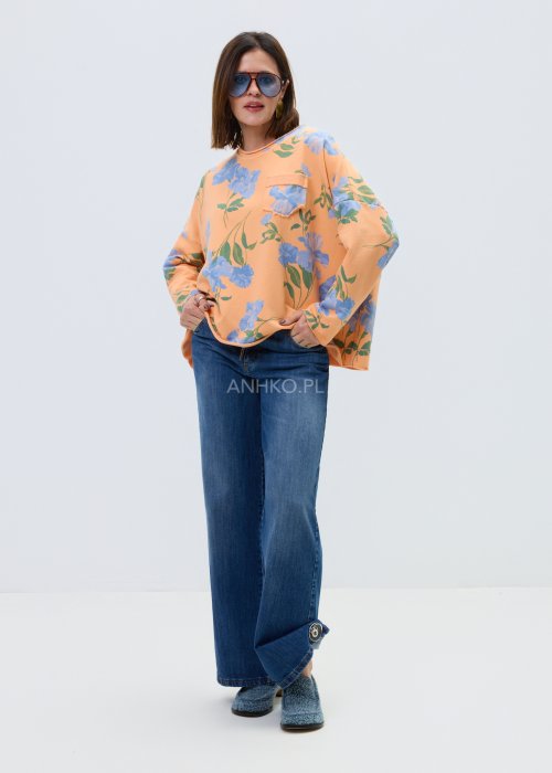 Damska bluza oversize w kolorze pomarańczowym z niebieskim kwiatowym wzorem, model z długim rękawem, zaokrąglonym dekoltem i kieszonką na piersi.