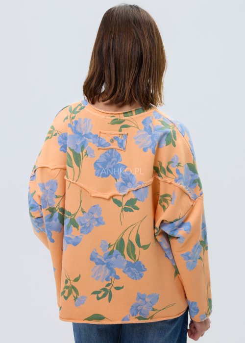 Damska bluza oversize w kolorze pomarańczowym z niebieskim kwiatowym wzorem, model z długim rękawem, zaokrąglonym dekoltem i kieszonką na piersi.