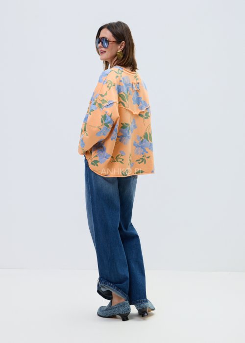 Damska bluza oversize w kolorze pomarańczowym z niebieskim kwiatowym wzorem, model z długim rękawem, zaokrąglonym dekoltem i kieszonką na piersi.