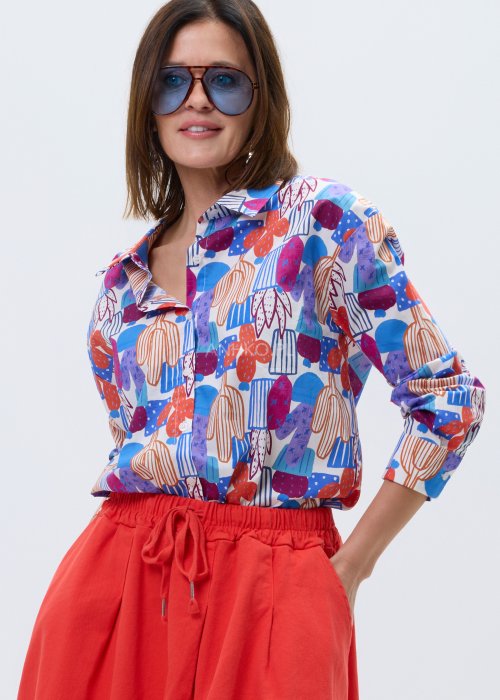 Kolorowa damska koszula z długim rękawem i geometryczno-roślinnym wzorem, stylizowana z jasnymi spodniami lub czerwonymi spodniami z wysokim stanem