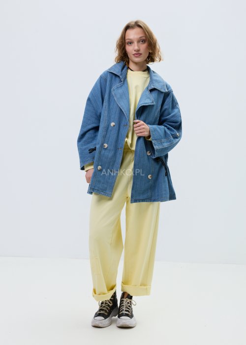 Niebieska kurtka jeansowa oversize z szerokim kołnierzem i zapięciem na guziki, z regulacją w talii na troczki. Stylizacja z jasnym topem i spodniami w nowoczesnym, miejskim stylu.
