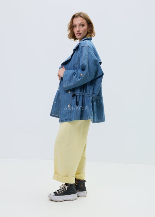 Niebieska kurtka jeansowa oversize z szerokim kołnierzem i zapięciem na guziki, z regulacją w talii na troczki. Stylizacja z jasnym topem i spodniami w nowoczesnym, miejskim stylu.