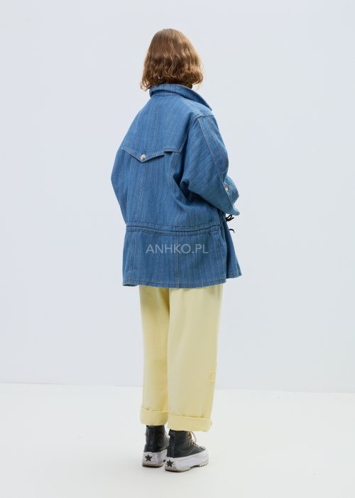 Niebieska kurtka jeansowa oversize z szerokim kołnierzem i zapięciem na guziki, z regulacją w talii na troczki. Stylizacja z jasnym topem i spodniami w nowoczesnym, miejskim stylu.