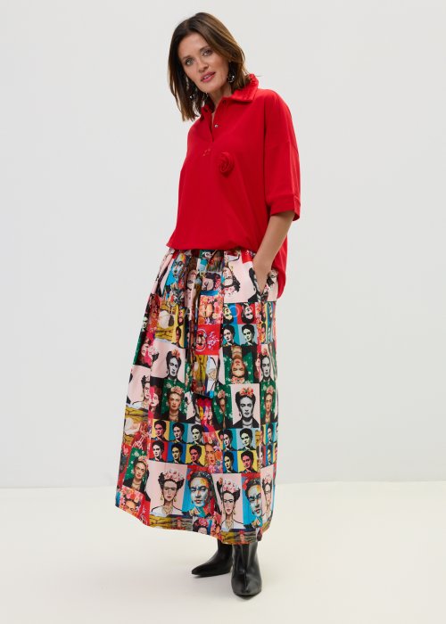 Czerwona bluzka damska oversize z dekoltem polo i zatrzaskami, z szerokimi rękawami, stylizowana ze wzorzystą spódnicą.