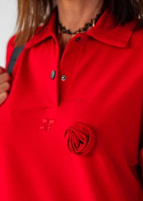 Czerwona bluzka damska oversize z dekoltem polo i zatrzaskami, z szerokimi rękawami, stylizowana ze wzorzystą spódnicą.