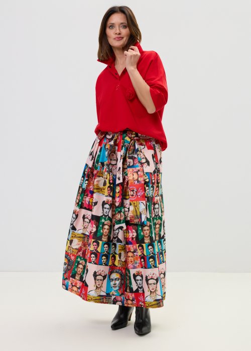 Czerwona bluzka damska oversize z dekoltem polo i zatrzaskami, z szerokimi rękawami, stylizowana ze wzorzystą spódnicą.