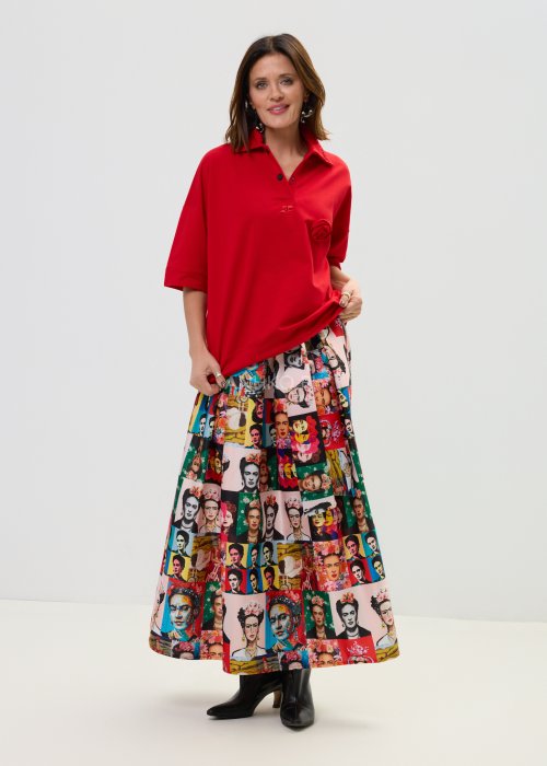 Czerwona bluzka damska oversize z dekoltem polo i zatrzaskami, z szerokimi rękawami, stylizowana ze wzorzystą spódnicą.