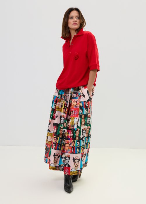 Czerwona bluzka damska oversize z dekoltem polo i zatrzaskami, z szerokimi rękawami, stylizowana ze wzorzystą spódnicą.