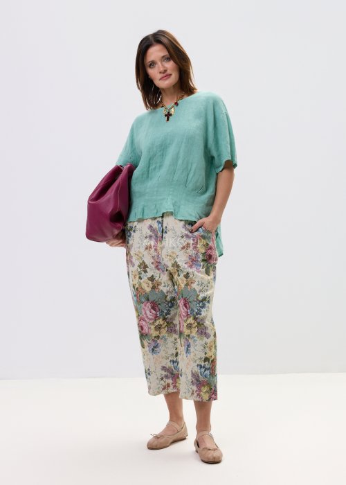 Wzorzyste spodnie damskie z motywem kwiatów, wykonane z tkaniny o strukturze, z kieszeniami po bokach.