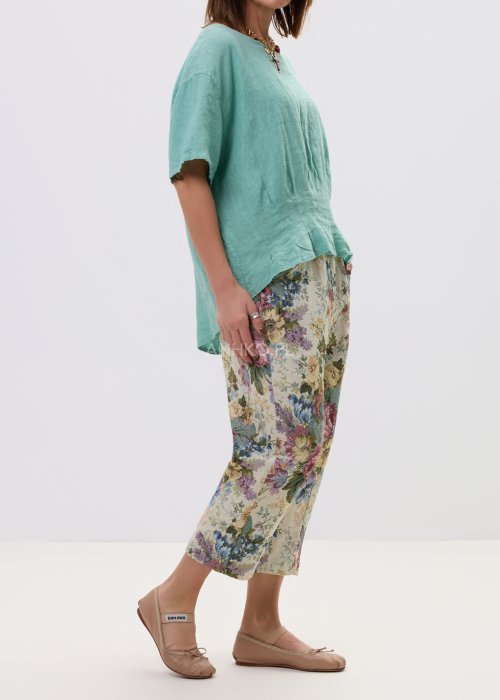 Wzorzyste spodnie damskie z motywem kwiatów, wykonane z tkaniny o strukturze, z kieszeniami po bokach.