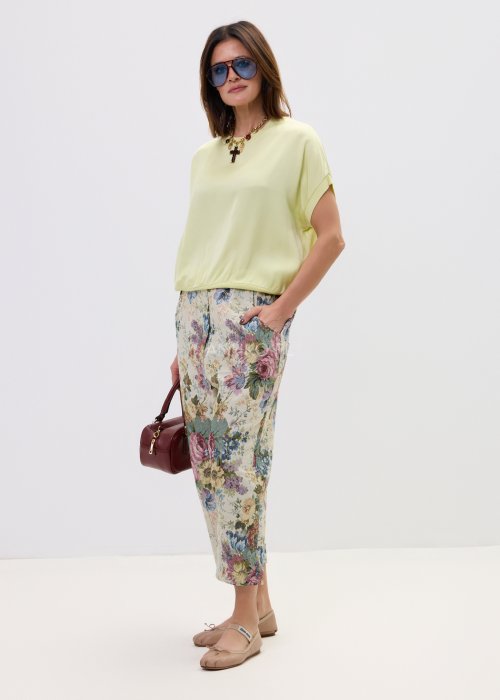 Wzorzyste spodnie damskie z motywem kwiatów, wykonane z tkaniny o strukturze, z kieszeniami po bokach.