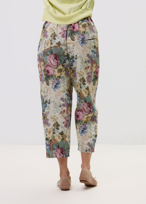 Wzorzyste spodnie damskie z motywem kwiatów, wykonane z tkaniny o strukturze, z kieszeniami po bokach.