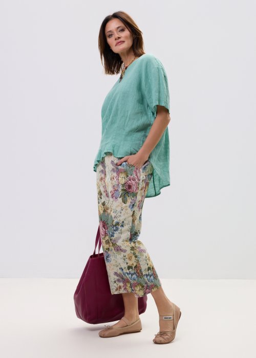 Wzorzyste spodnie damskie z motywem kwiatów, wykonane z tkaniny o strukturze, z kieszeniami po bokach.