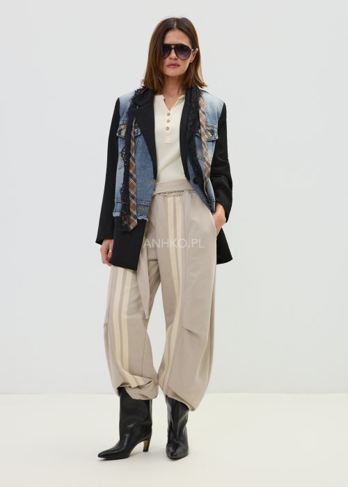 Spodnie damskie beżowe z luźnym krojem, szeroką nogawką i ozdobnymi paskami po bokach.