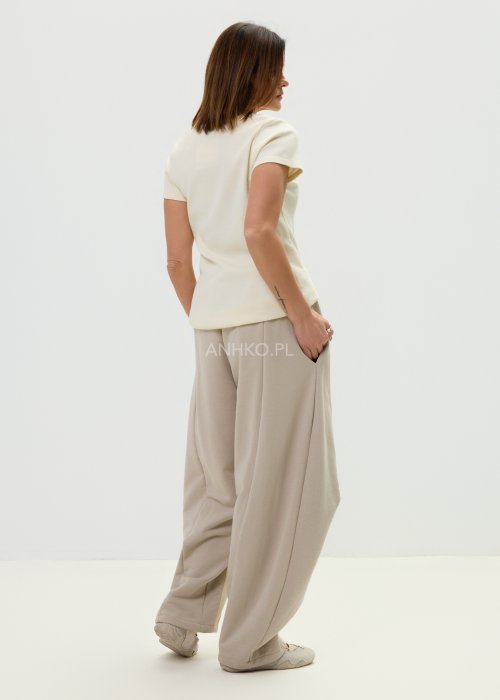 Spodnie damskie beżowe z luźnym krojem, szeroką nogawką i ozdobnymi paskami po bokach.