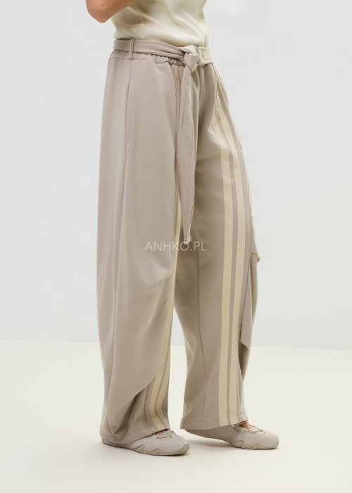 Spodnie damskie beżowe z luźnym krojem, szeroką nogawką i ozdobnymi paskami po bokach.
