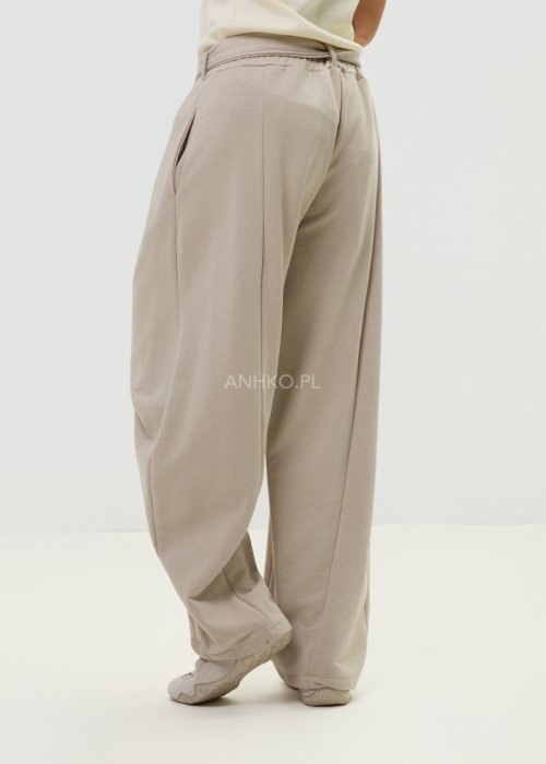 Spodnie damskie beżowe z luźnym krojem, szeroką nogawką i ozdobnymi paskami po bokach.
