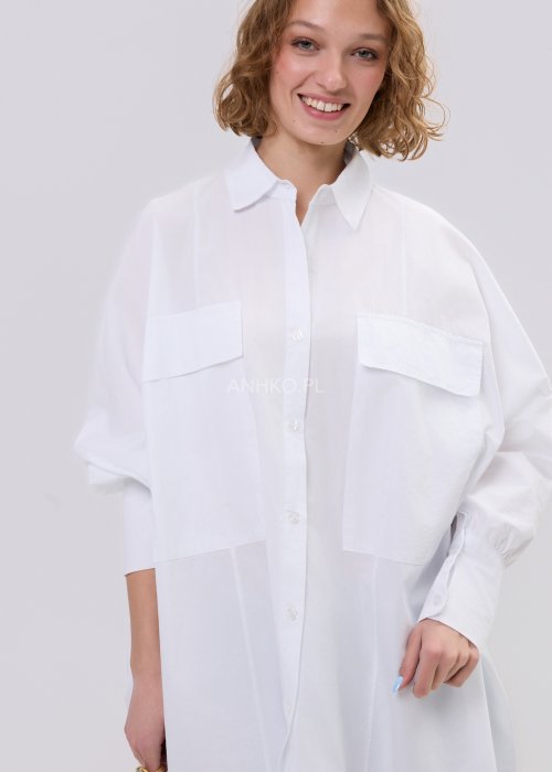 Biała koszula damska oversize o dłuższym fasonie z kołnierzem i kieszenią na piersi, z długim rękawem i zapięciem na guziki.