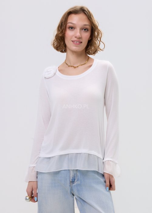 Biała bluzka damska z długim rękawem i delikatną falbaną na dole oraz przy mankietach, z ozdobnym kwiatem przy dekolcie.