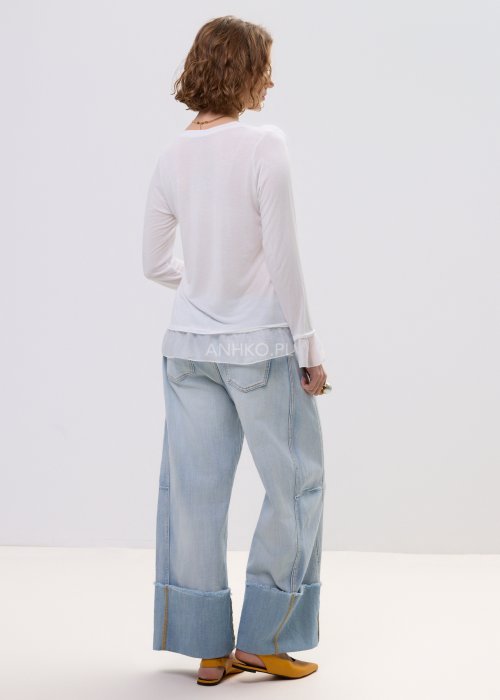 Biała bluzka damska z długim rękawem i delikatną falbaną na dole oraz przy mankietach, z ozdobnym kwiatem przy dekolcie.