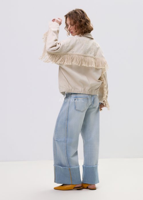 Beżowa kurtka damska z frędzlami i haftowanymi zdobieniami, zapinana na zamek, z kołnierzem i luźnym fasonem.