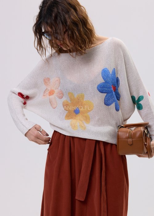 Kremowy sweter damski o luźnym kroju z kolorowym motywem kwiatów, z szerokim dekoltem i długim rękawem, stylizowany ze spódnicą maxi.