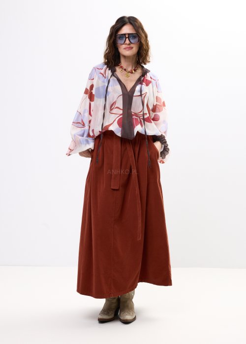 Spódnica sztruksowa maxi w kolorze ceglastym z wysokim stanem i paskiem do wiązania, o rozkloszowanym fasonie, stylizowana z lekką bluzką i botkami w stylu boho.