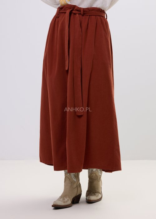 Spódnica sztruksowa maxi w kolorze ceglastym z wysokim stanem i paskiem do wiązania, o rozkloszowanym fasonie, stylizowana z lekką bluzką i botkami w stylu boho.