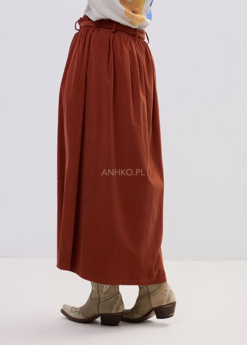 Spódnica sztruksowa maxi w kolorze ceglastym z wysokim stanem i paskiem do wiązania, o rozkloszowanym fasonie, stylizowana z lekką bluzką i botkami w stylu boho.