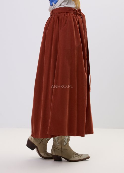 Spódnica sztruksowa maxi w kolorze ceglastym z wysokim stanem i paskiem do wiązania, o rozkloszowanym fasonie, stylizowana z lekką bluzką i botkami w stylu boho.