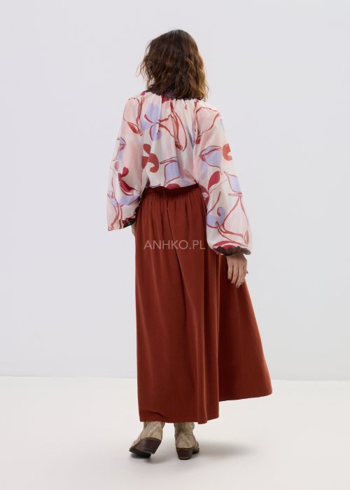 Spódnica sztruksowa maxi w kolorze ceglastym z wysokim stanem i paskiem do wiązania, o rozkloszowanym fasonie, stylizowana z lekką bluzką i botkami w stylu boho.