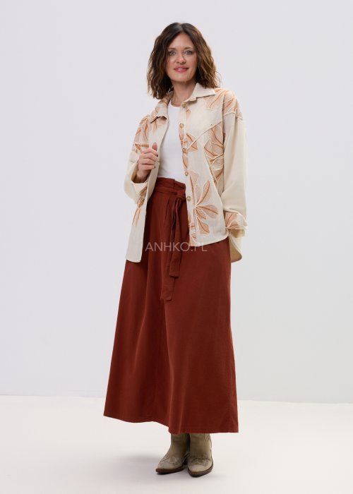 Koszula damska beżowa z haftowanym wzorem roślinnym w odcieniach karmelu, zapinana na guziki, z szerokim rękawem, stylizowana ze spódnicą midi.