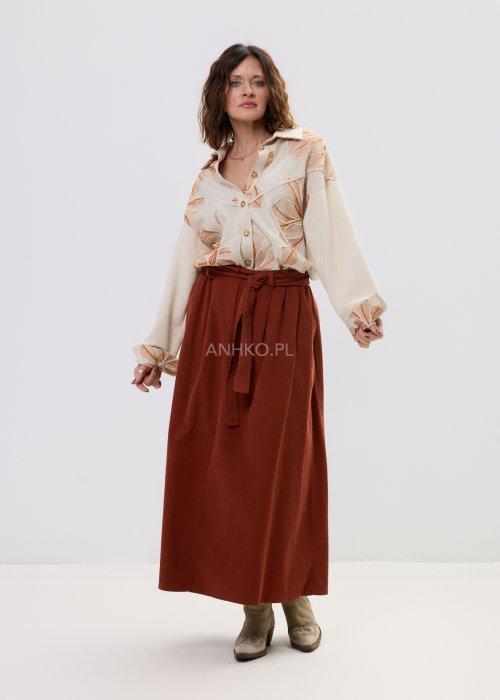 Koszula damska beżowa z haftowanym wzorem roślinnym w odcieniach karmelu, zapinana na guziki, z szerokim rękawem, stylizowana ze spódnicą midi.