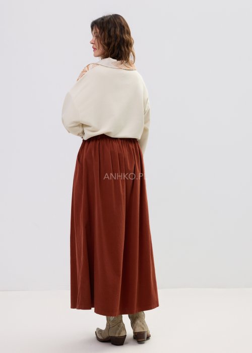 Koszula damska beżowa z haftowanym wzorem roślinnym w odcieniach karmelu, zapinana na guziki, z szerokim rękawem, stylizowana ze spódnicą midi.